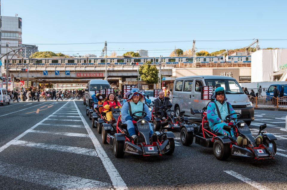 Tourists driving go-karts wait in heavy traffic on an eight lane highway while wearing costumes.